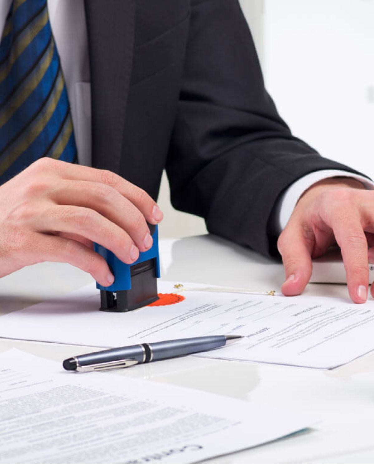 Ein Mann in formeller Kleidung verwendet einen Stempel, um ein Dokument zu signieren